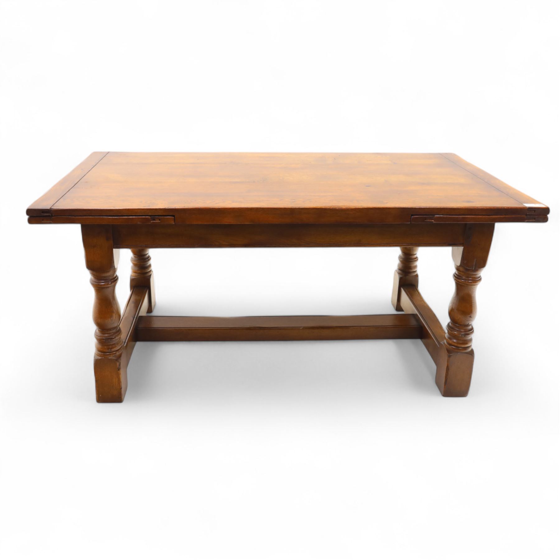 20th-century good quality solid oak extending refectory table, planked, constructed rectangular top with two extending leaves on the underside above a plain frieze raised on four turned baluster supports united by stretchers on block feet, 260cm extended