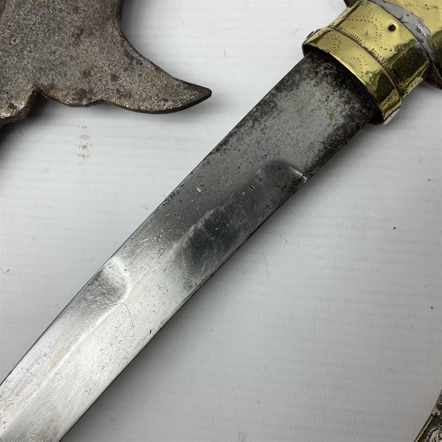 Moroccan jambiya dagger with 24.5cm plain curved blade stamped LONDON to the ricasso area, the hilt and scabbard overlaid with plain sheet brass to the back and ornate silver coloured metal to the front; waisted grip and arched pommel; two pyramid mounts to the scabbard L41cm overall; large billhook with curving blade and stacked leather washer grip; and a reproduction halberd blade (3)
