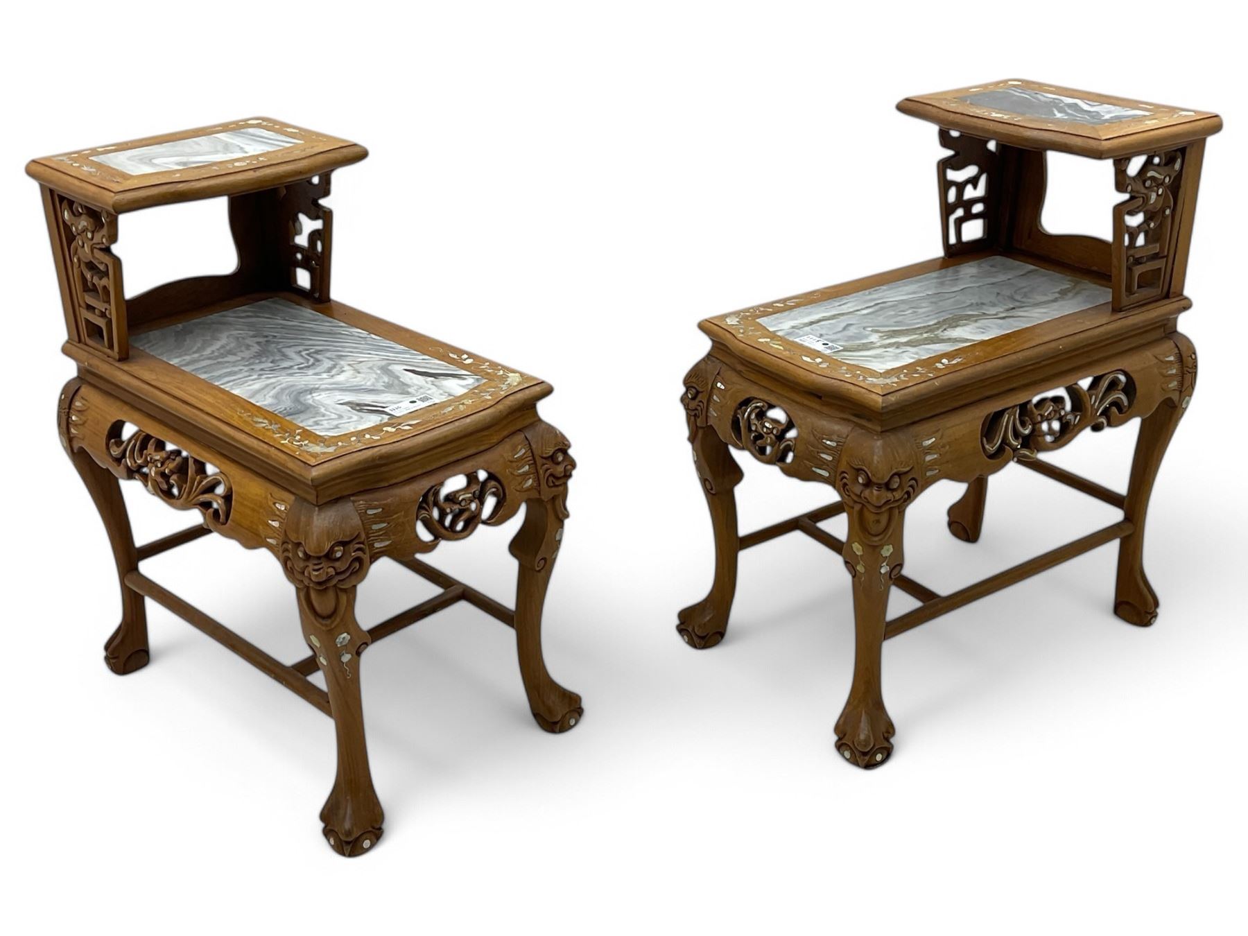 Pair of Chinese hardwood side or end tables, two moulded tiers with grey marble insets, inlaid with trailing foliate motifs in mother of pearl, with scrolling fretwork frieze rails, on cabriole supports with ball and claw feet united by plain stretchers 