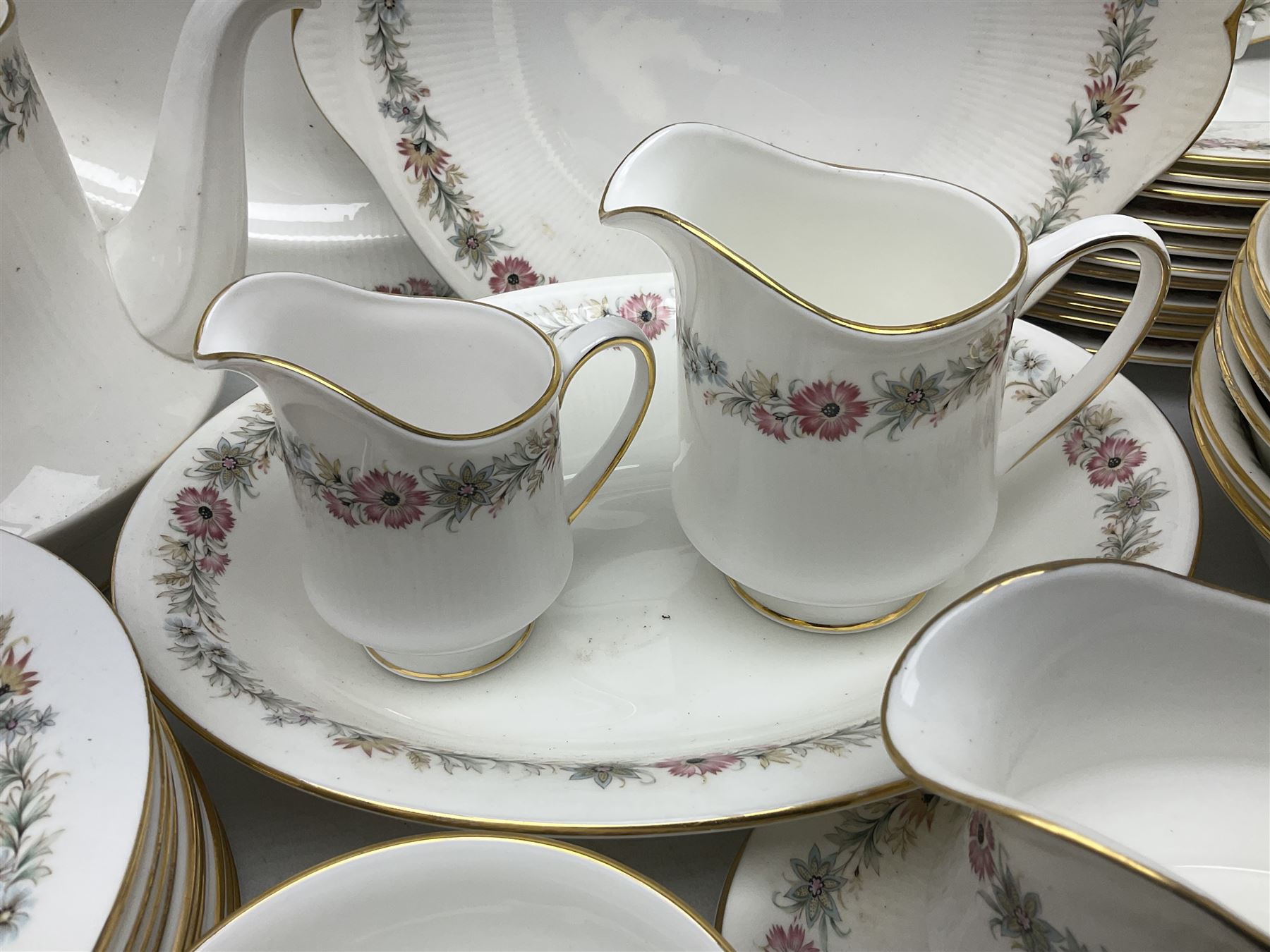 Royal Albert Paragon tea and dinner service for twelve decorated in the Belinda pattern, comprising fourteen saucers, twelve teacups, thirteen side plates, teapot, sauce boat and stand, salt and pepper shakers, two jugs, sucrier, twelve dinner plates, twelve smaller plates, two lidded tureens, twelve bowls, twelve smaller bowls, cake plate, oval plate and oval dish (100)