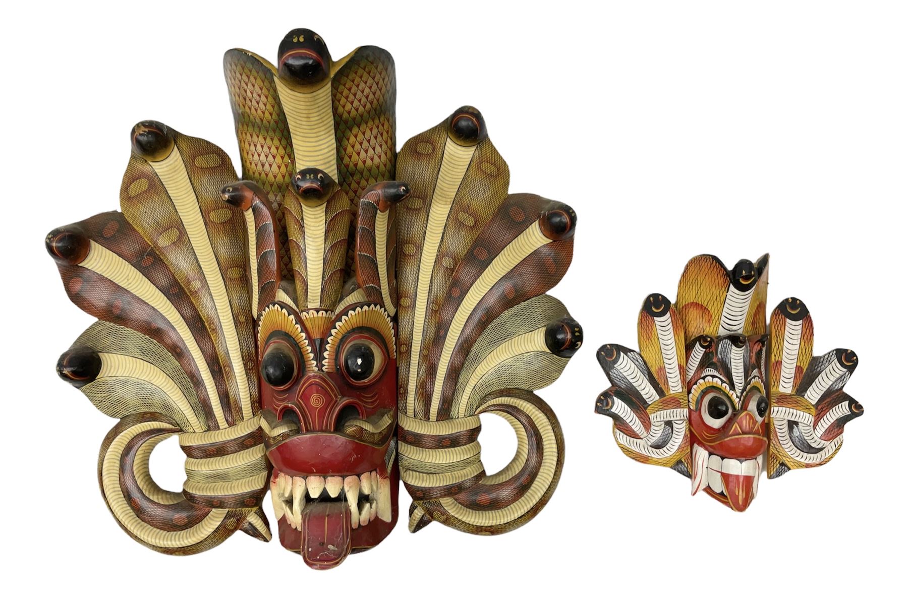 Sri Lankan Cobra mask depicting the demon Naga Raksha, together with a smaller example, largest H46cm
