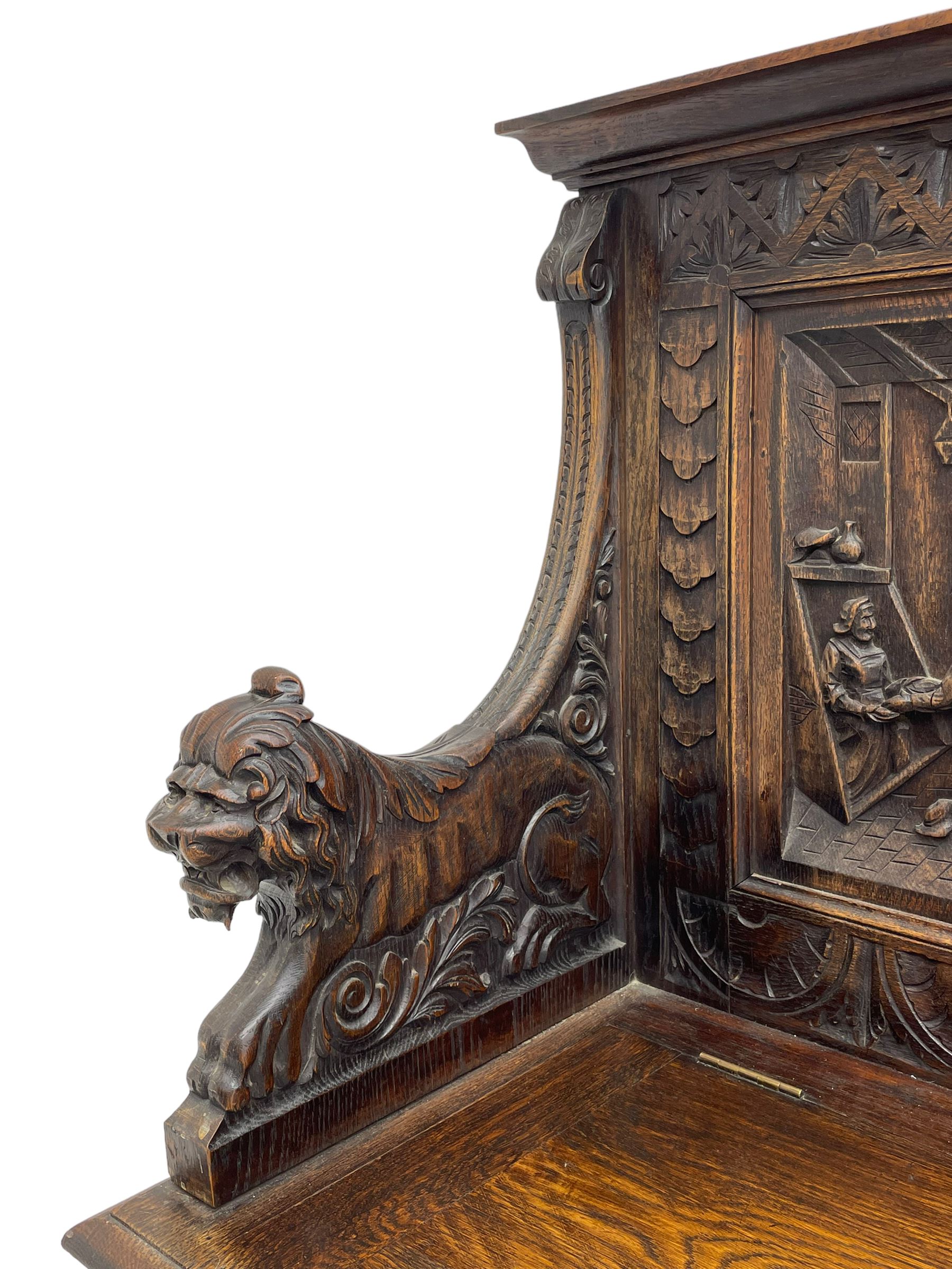 19th century heavily carved oak settle, the moulded upper rail over triangular foliage carved frieze, three Flemish style carved panels depicting tavern scenes, acanthus carved uprights terminating to lion carved arms, hinged box seat, the panelled front carved with lion masks and extending scrolled acanthus leaves, on moulded skirt base