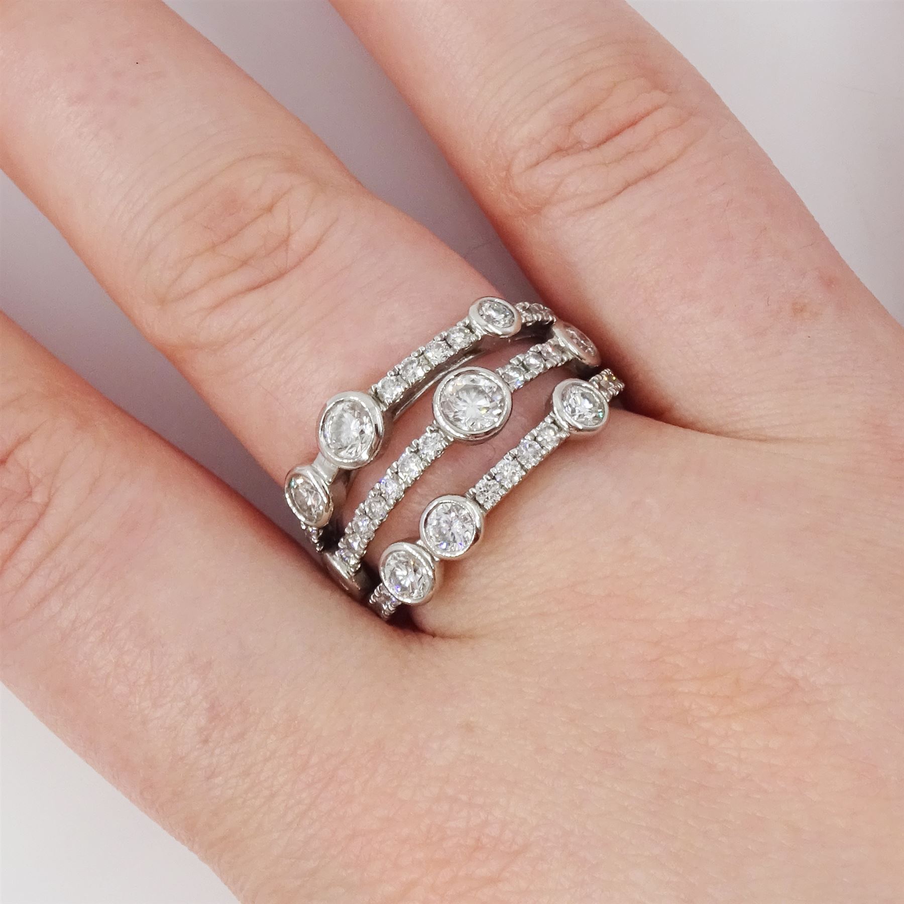 Platinum diamond three row split design ring, nine bezel set round brilliant cut diamonds, spaced by smaller round brilliant cut diamonds, hallmarked, total diamond weight 1.70 carat 