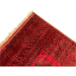 Persian Bokhara crimson ground carpet, the field decorated with three rows of Gul motifs, the multi-band border with alternating geometric patterns