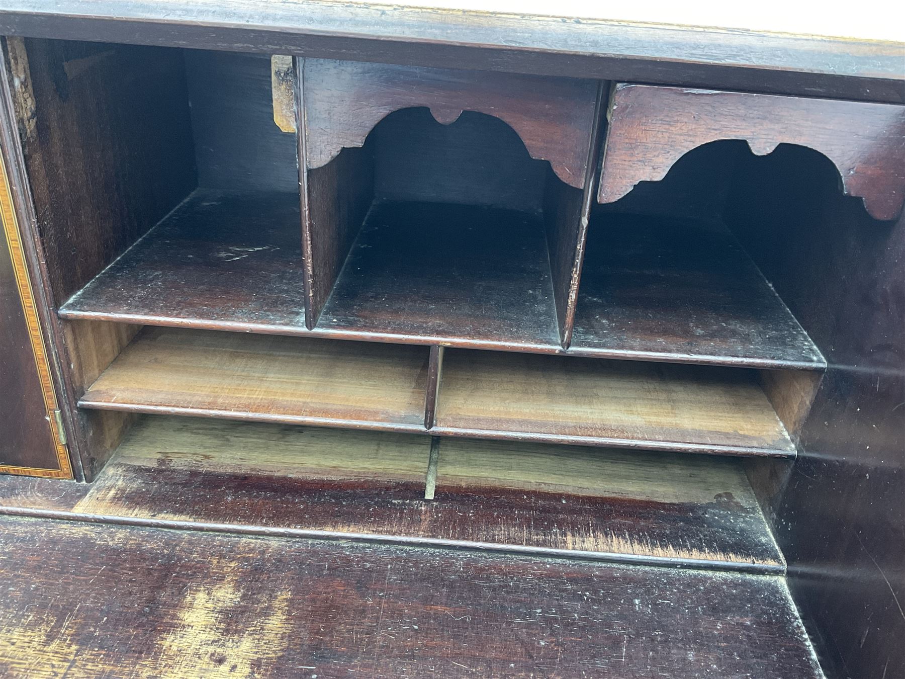 George III mahogany bureau, the conch inlaid fall front enclosing pigeon holes, shelves and central cupboard with inlaid flower motif, four graduating cock-beaded drawers below each with brass handles, lower moulded edge over shaped bracket feet