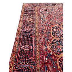 Antique Persian coral ground carpet, the large central floral pole medallion with extending foliate designs, the thick guarded indigo border with repeating flower heads and circles