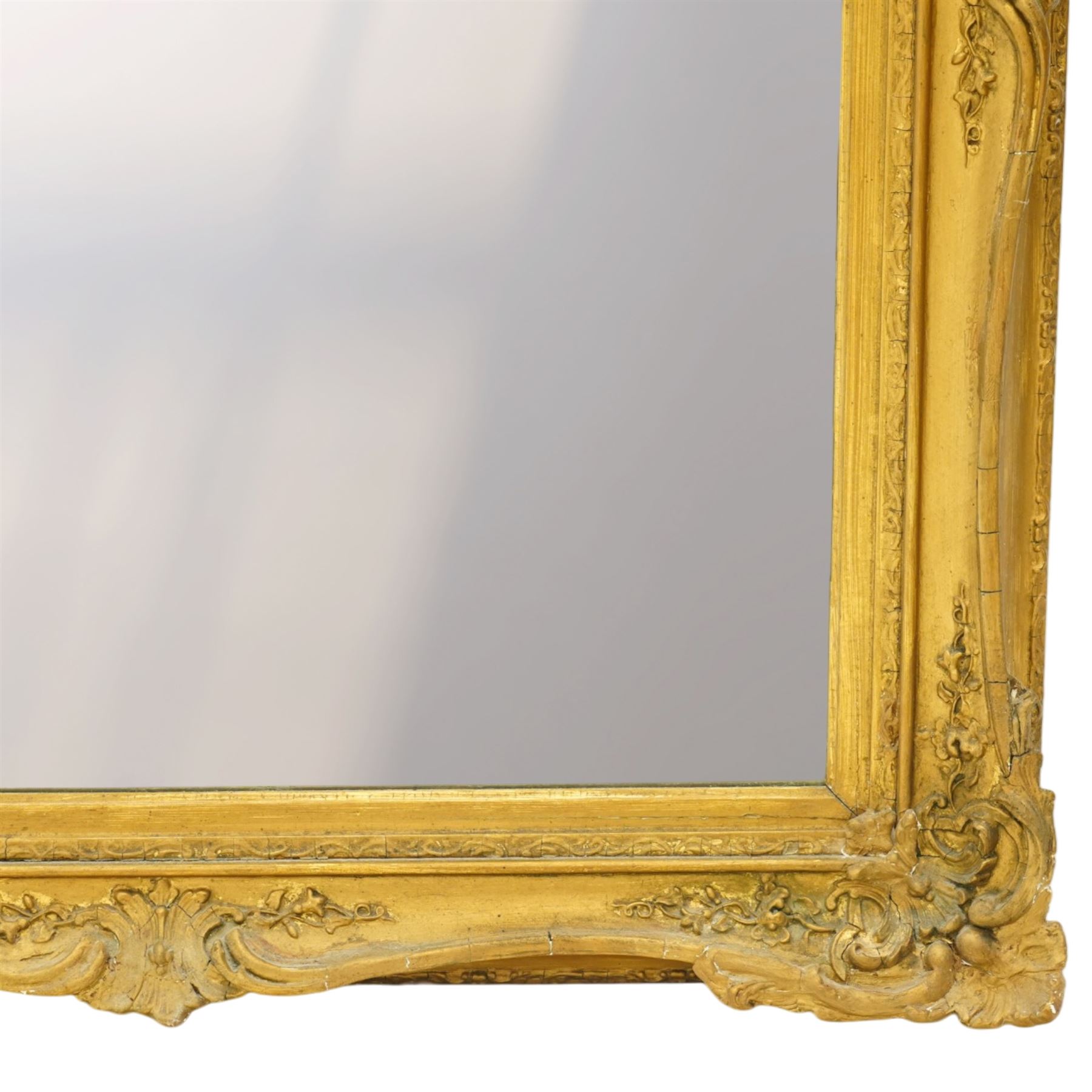 French style gilt composition wall mirror, the rectangular plate within a swept frame moulded with scrolling foliage and shell motifs