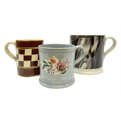 Three 19th century mochaware type cups, comprising an engine turned cream and brown checkerboard example, together with a marbled effect example with gilt upper banding and cream base, interior and handle, and a further smaller blue cup moulded and painted with floral motifs on pale blue ground, largest H8.5cm