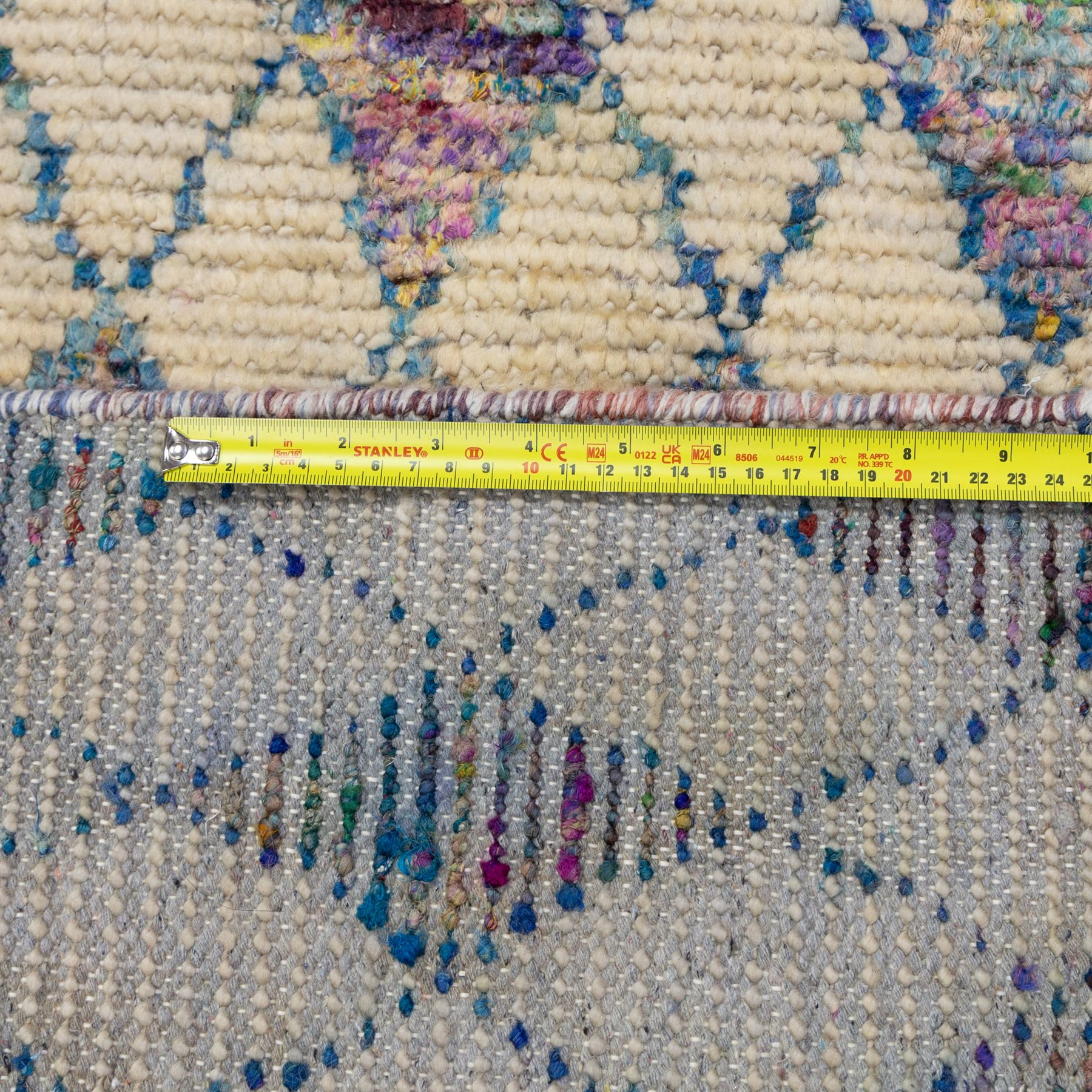 Contemporary Moroccan Berber design wool rug, cream field with blue diamond lattice, decorated with repeating multicoloured lozenge motifs, short fringe ends and bound sides
