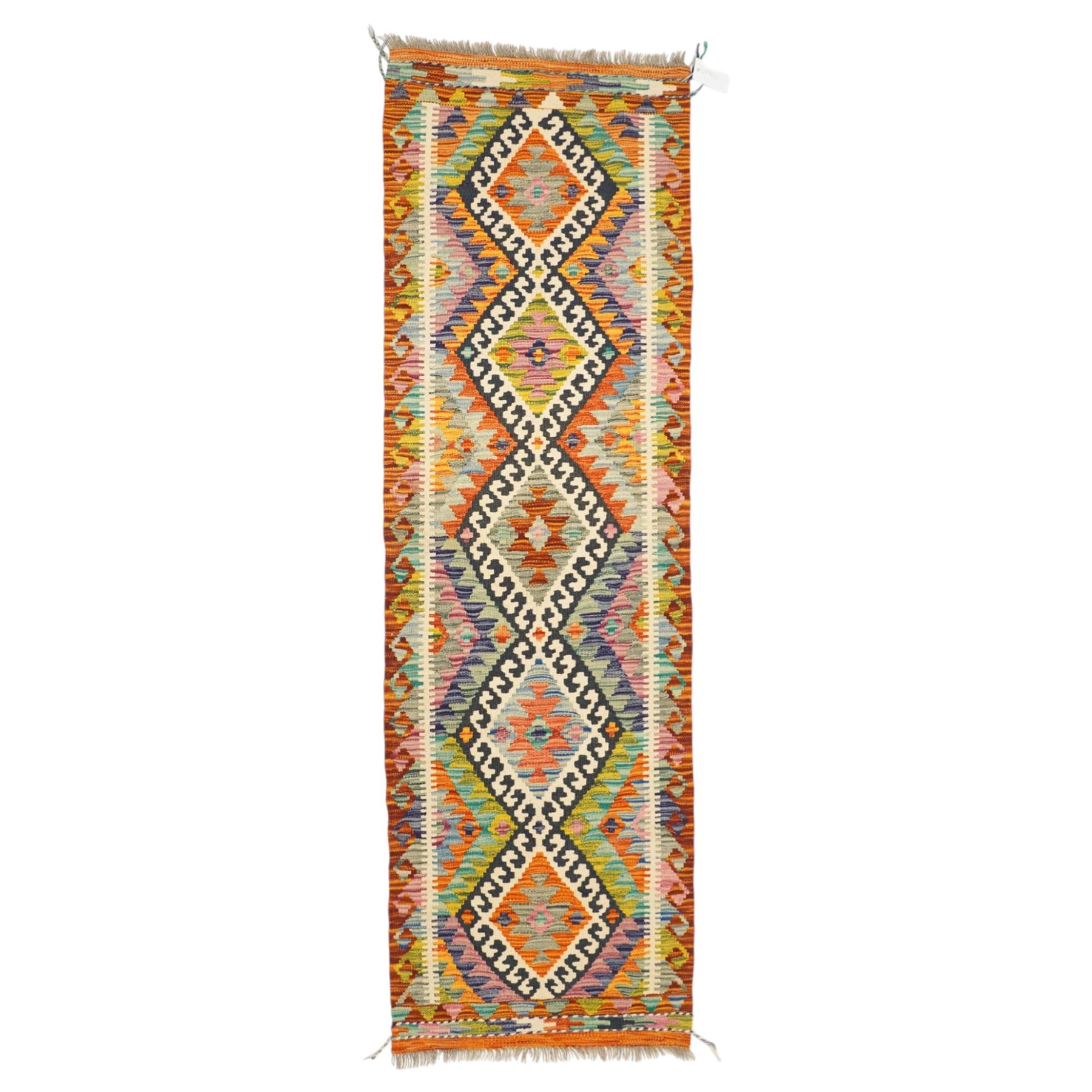 Afghan Chobi flatweave kilim runner, with a repeating stepped diamond medallion design in ivory, green, rust, teal, purple, indigo, and framed by chevron and geometric borders