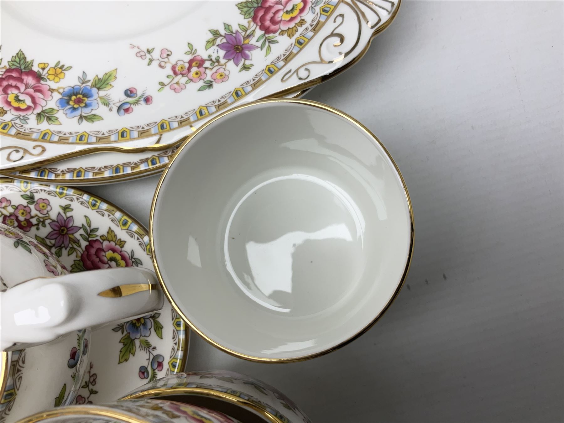 Extensive Royal Grafton Malvern pattern tea and dinner wares, comprising twelve dinner plates, six smaller plates, coffee pot, two teapots, two cake plates, eight teacups and ten saucers, six coffee cups and six saucers, two open sucriers, twin handled lidded sucrier, jug, lidded mustard pot and condiment jar, lidded tureen, two circular twin handled vegetable tureens, sauce boat and stand, oval and circular serving plates, salt and pepper shakers, breakfast cup and two saucers, further large cup and saucer, eighteen tea plates of various shapes, six side plates, six cereal bowls and six further bowls, shell dish and dish of square form, fork and knife, together with a hallmarked silver condiment spoon