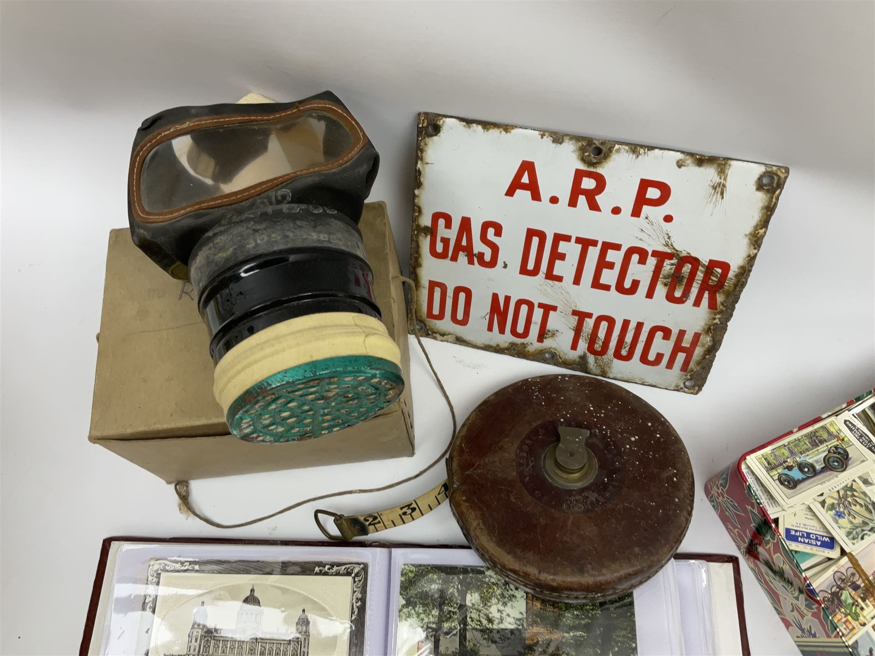 Postcards including WW1 silk postcards, local interest and photographic postcards, gas mask in box, material tape measure and metal sign. 