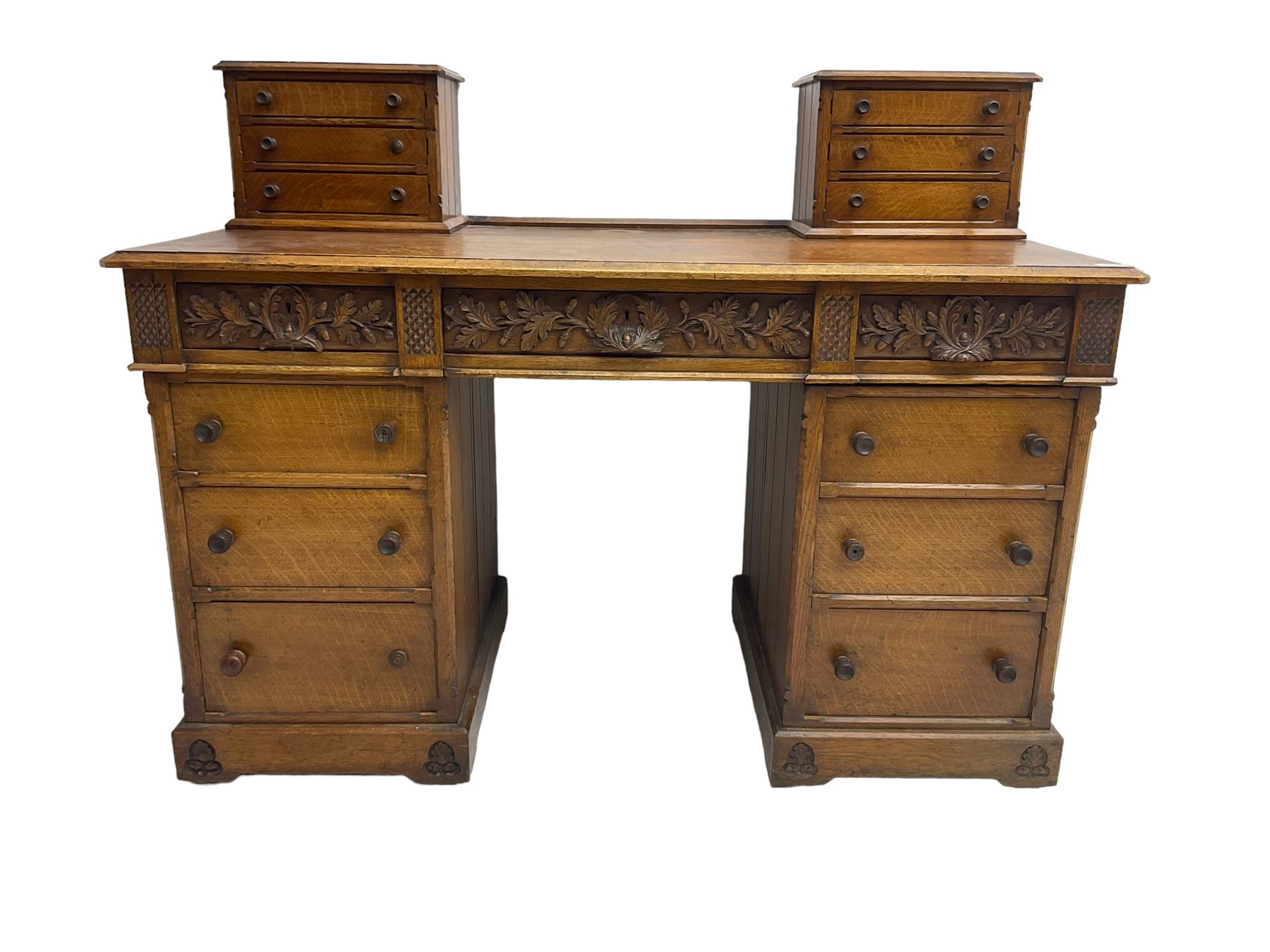 Late 19th century heavily carved oak twin pedestal desk, rectangular top with two raised trinket or correspondence structures each with three drawers, rectangular top over three frieze drawers carved with acorn and oak leaf decoration, each pedestal with three drawers with acorn husk shaped handles