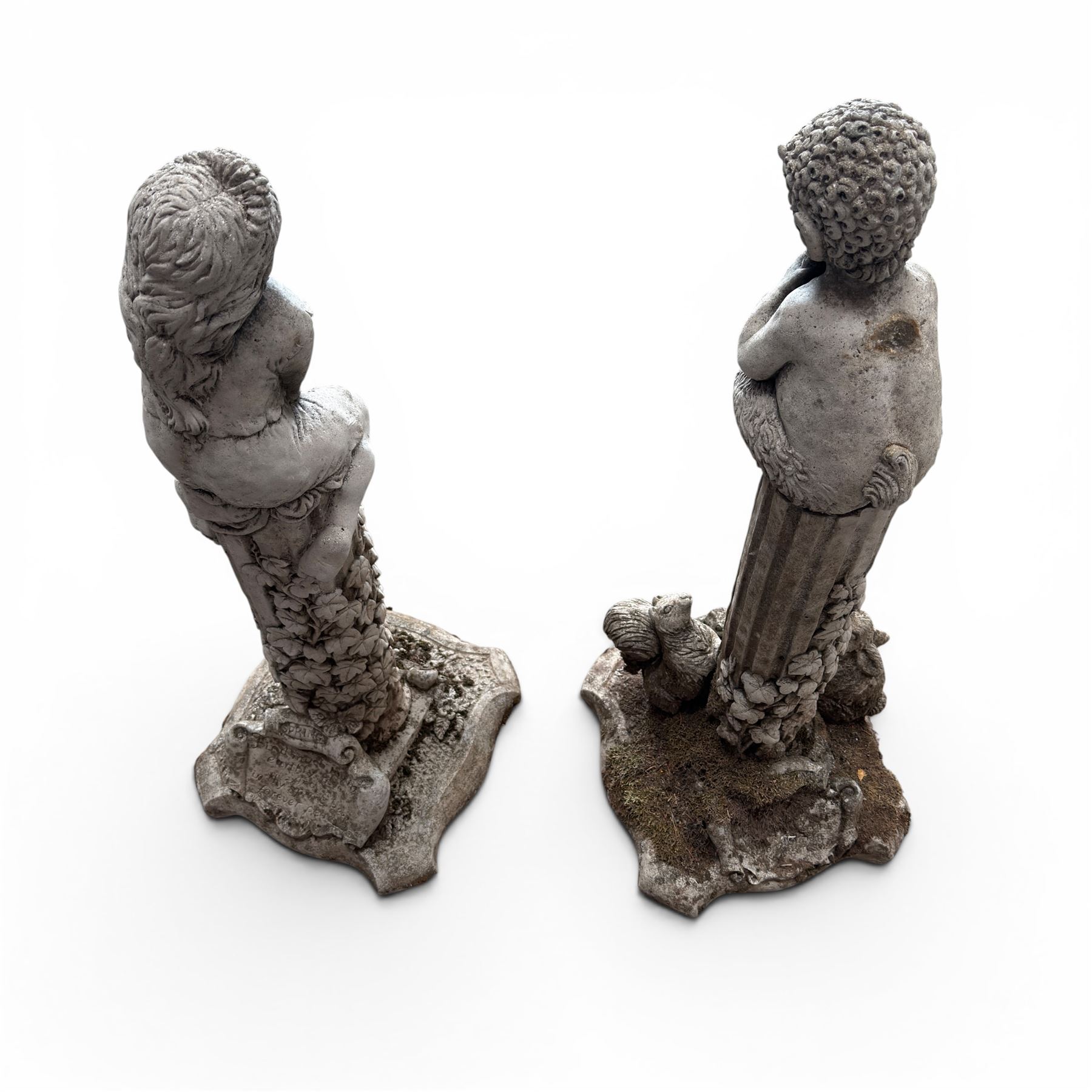 Pair of weathered composite stone garden figures, modelled as a girl and a young satyr playing the panpipes seated on column supports, the fluted columns with climbing ivy vines and surmounted animal, butterfly and other zoomorphic motifs