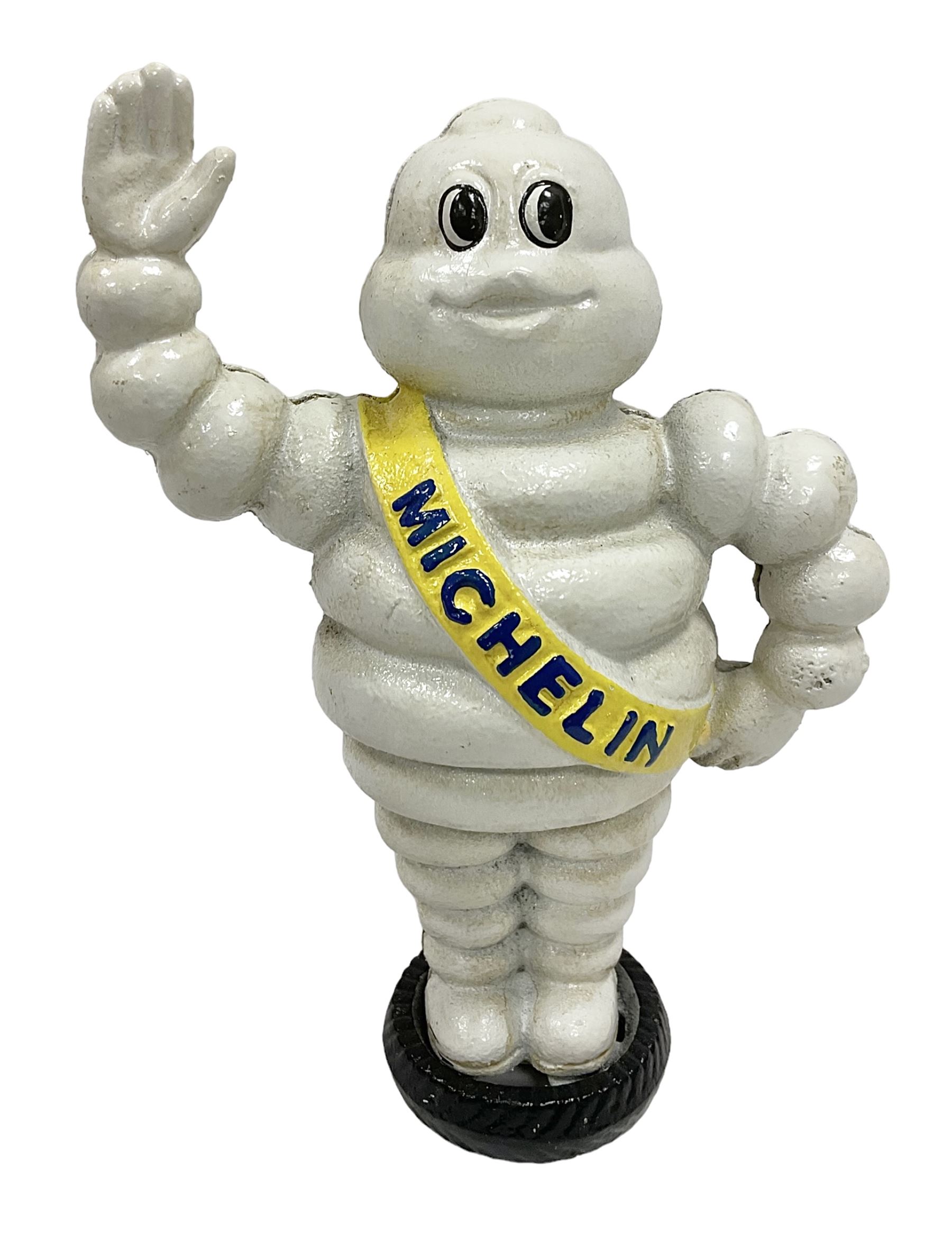 Cast iron money bank of a waving Michelin man stood on a tyre, H23cm
