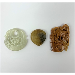 Two Russet carved jade pendants, one with zoomorphic detail, the other with floral detail, largest H6cm, together with a celadon jade pendant or bi disc, also with carved zoomorphic detail, D5cm. (3).