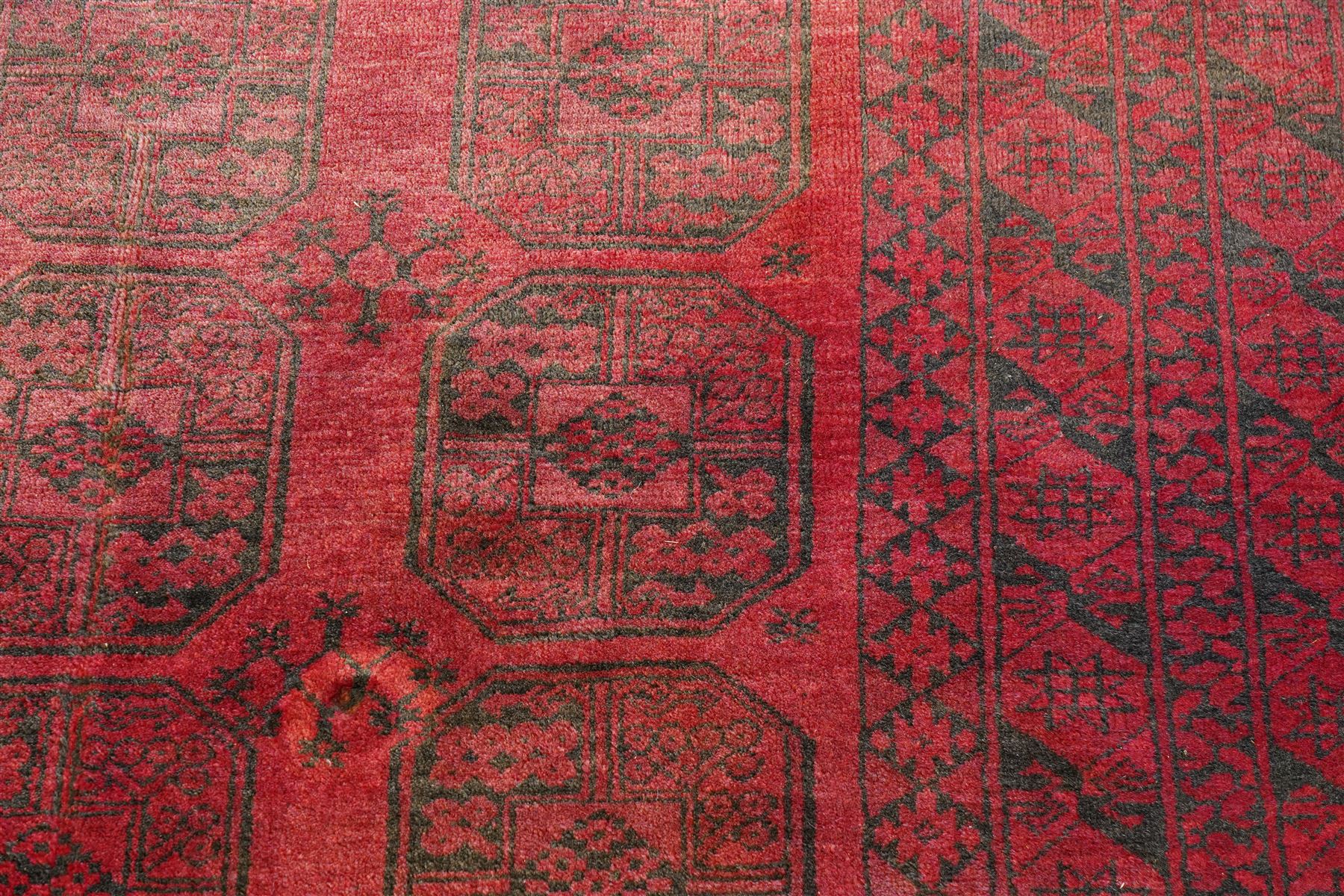 Afghan crimson ground Bokhara rug, the field with three rows of repeating Gul motifs, within six concentric guard bands decorated with repeating geometric patterns