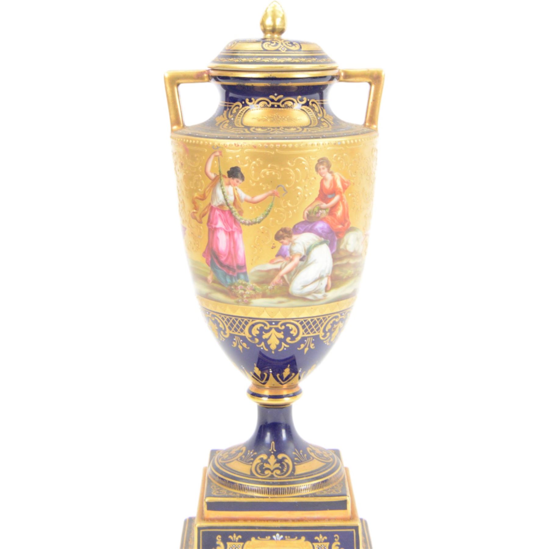 Late 19th century Vienna twin handled urn and cover decorated with classical figures on a textured gilt ground,  upon a square stepped cobalt blue pedestal with gilt detailing, H36cm