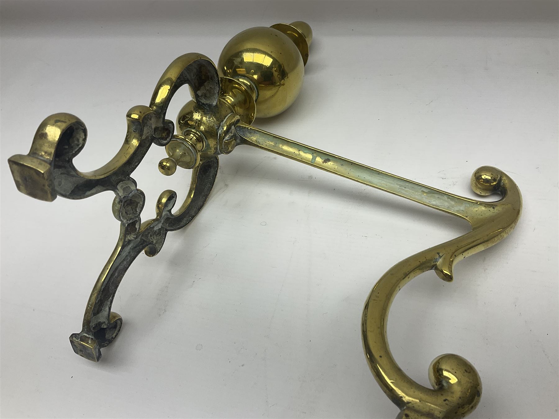 Pair of early 20th century brass fire dogs, each with sphere and urn finial, upon a scrolling base, H38cm