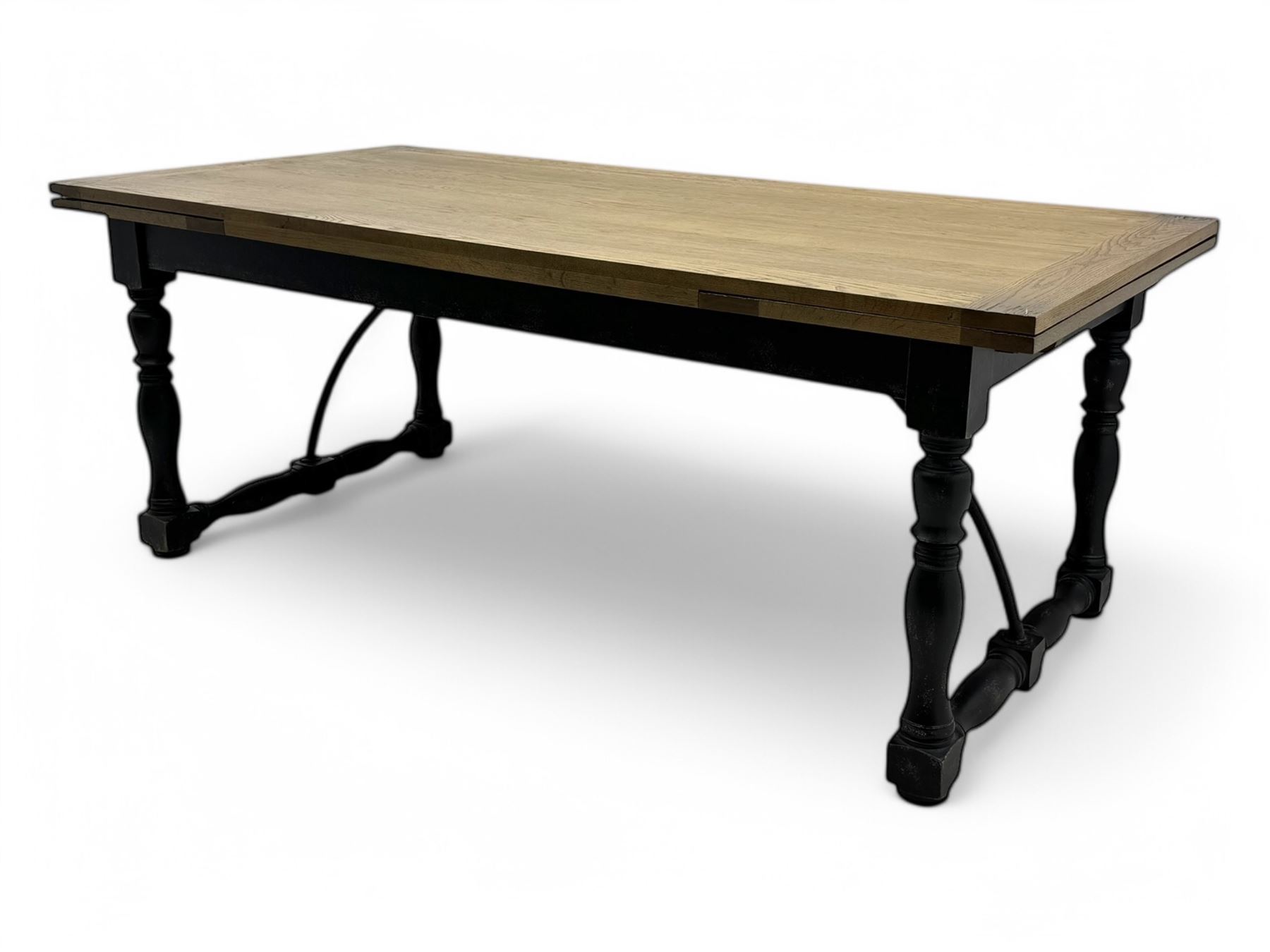 Barker & Stonehouse - large oak extending draw-leaf dining table, rectangular plank top over a black painted base, turned supports joined by shaped stretchers, extending at each end with pull-out leaves