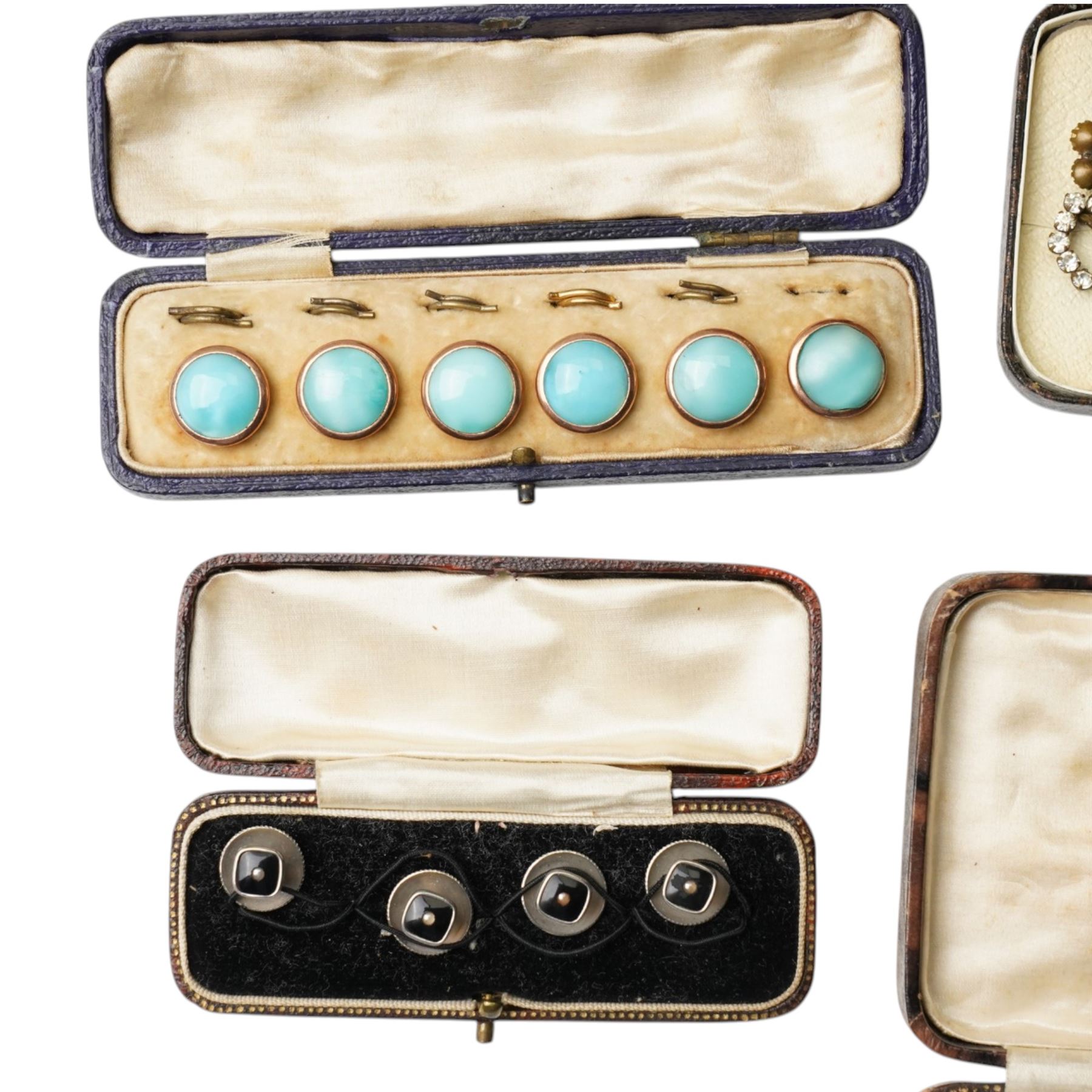 Early 20th century dress sets including onyx and paste examples, some stamped 935, paste set buckles and buttons, faux turquoise jabot pin, in the style of Bernard Instone, silver cufflinks etc, housed in an early 20th century red leather jewellery box