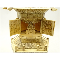  Early 20th century Chinese carved ivory Pagoda, the hexagonal sloping rood carved with a cockerel amongst lily pads, with two hinged doors opening to reveal a seated god, above two tiers carved with figures and dragons, on carved hardwood base, H40cm   