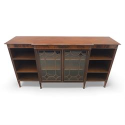 Early 20th century mahogany breakfront bookcase cabinet, the moulded rectangular top above a central pair of astragal glazed doors with arched glazing bars enclosing shelving, flanked by open book shelves, raised on square tapering supports with block feet
