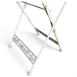 Three-piece French style white-painted wrought iron garden bistro set, comprising a circular folding table with latticework top and apron with scrolling foliate motifs (W70cm H80cm) and matching pair of chairs, with scrolling cresting rail and acorn finials over a scrolled foliate medallion, raised on lattice seat and folding X-frame base (W42cm H93cm)