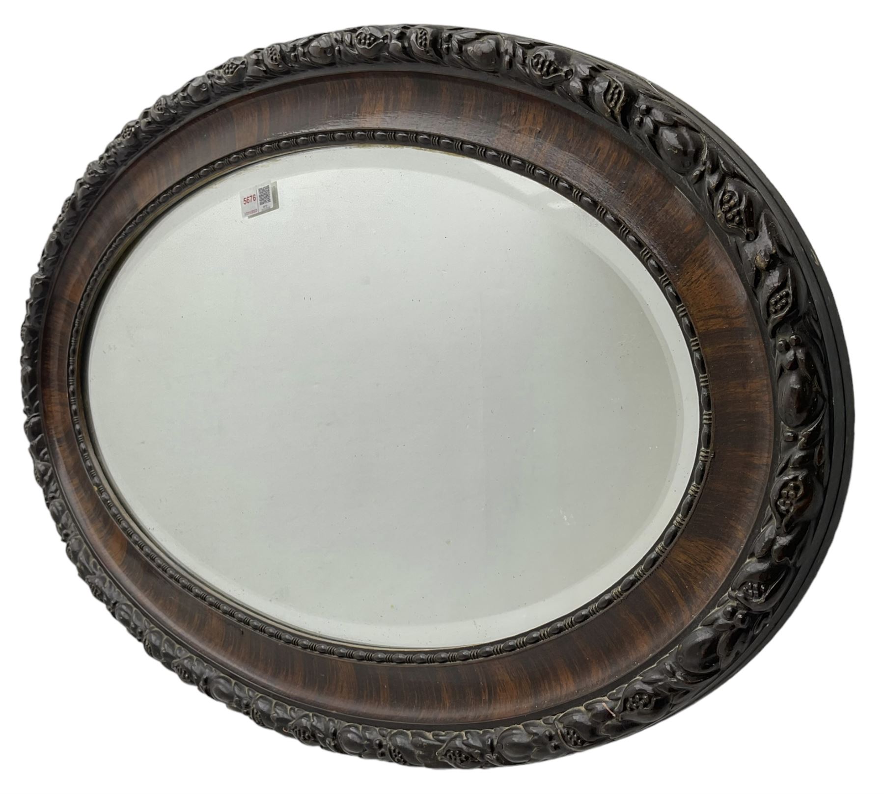 Early 20th century oval mirror, moulded frame decorated with trailing foliage and berries, bevelled plate