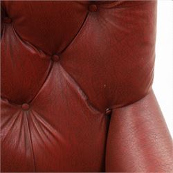 Early 20th century style oxblood red leather Chesterfield armchair, deep buttoned shaped back over padded scroll arms and loose seat cushion, raised on turned mahogany front supports with brass caps and castors