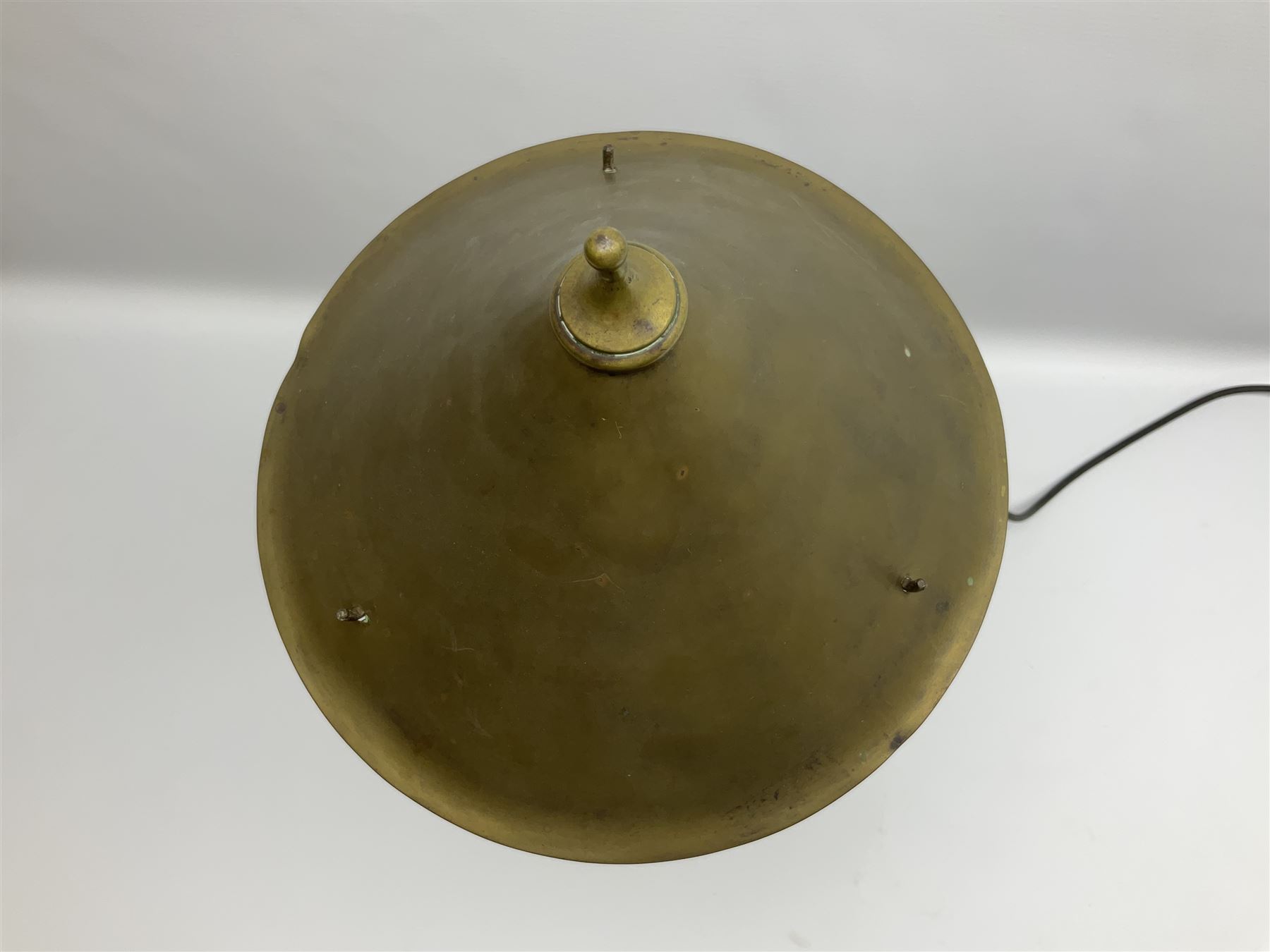 Arts & Crafts Jesson, Birkett & Co, brass table lamp or wall light, designed by Thomas Birkett, the tapering stem with adjustable ball pivot supporting a conical shade with tapering final with ball terminal, upon a circular domed base pierced for wall mounting, shade positioned upright overall H57cm

Often misattributed to Arthur Stansfield Dixon for Birmingham Guild of Handicraft, this particular lamp was designed by Thomas Birkett.
In the late 1890's Birkett worked as a metalwork at the Birmingham Guild, before later joining the Faulkner Bronze Company which went on to become Jesson, Birkett & Co in 1904. The lamp features in lighting catalogues from the firm under the model no E490.

