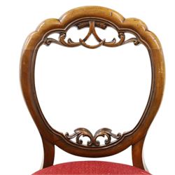 Set of five Victorian mahogany dining chairs, the scalloped balloon back with pierced scrolling acanthus leaf decoration, sprung seats upholstered in crimson fabric, on cabriole supports
