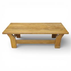 Modern oak coffee table, rectangular solid top with softly rounded edges, raised on shaped slab end supports united by a full-width stretcher