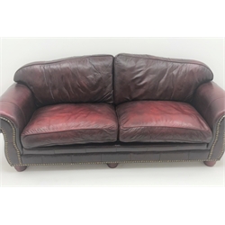  Three seat sofa upholstered in studded oxblood leather, arched back, scrolled arms, turned supports (W230cm) and matching two seat sofa (W177cm) (2)  
