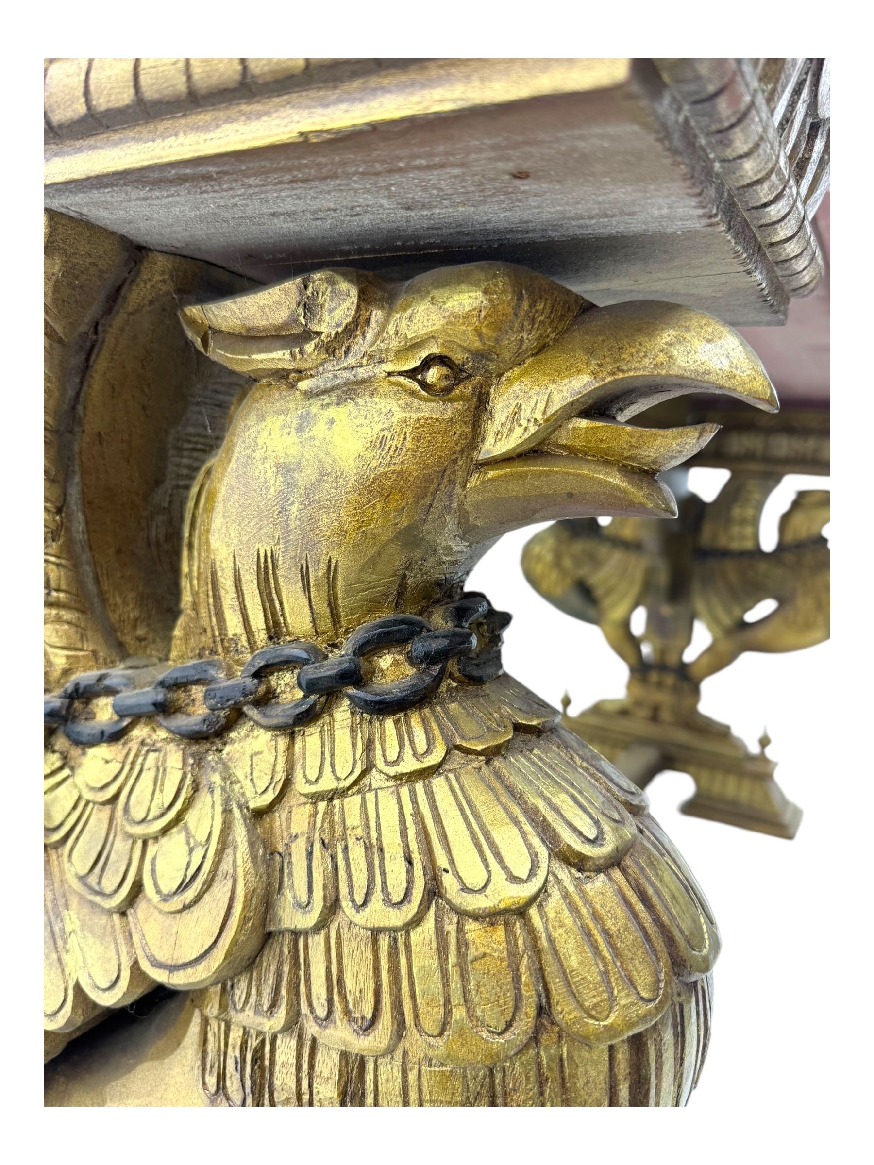 19th century Renaissance Revival carved and giltwood centre table, the rectangular top with gadrooned edge and carved frieze of repeating arched motifs with stylised scrolls, supported by a pair of carved winged griffin supports restrained by a central chained figure, on stepped rectangular bases united by carved stretcher