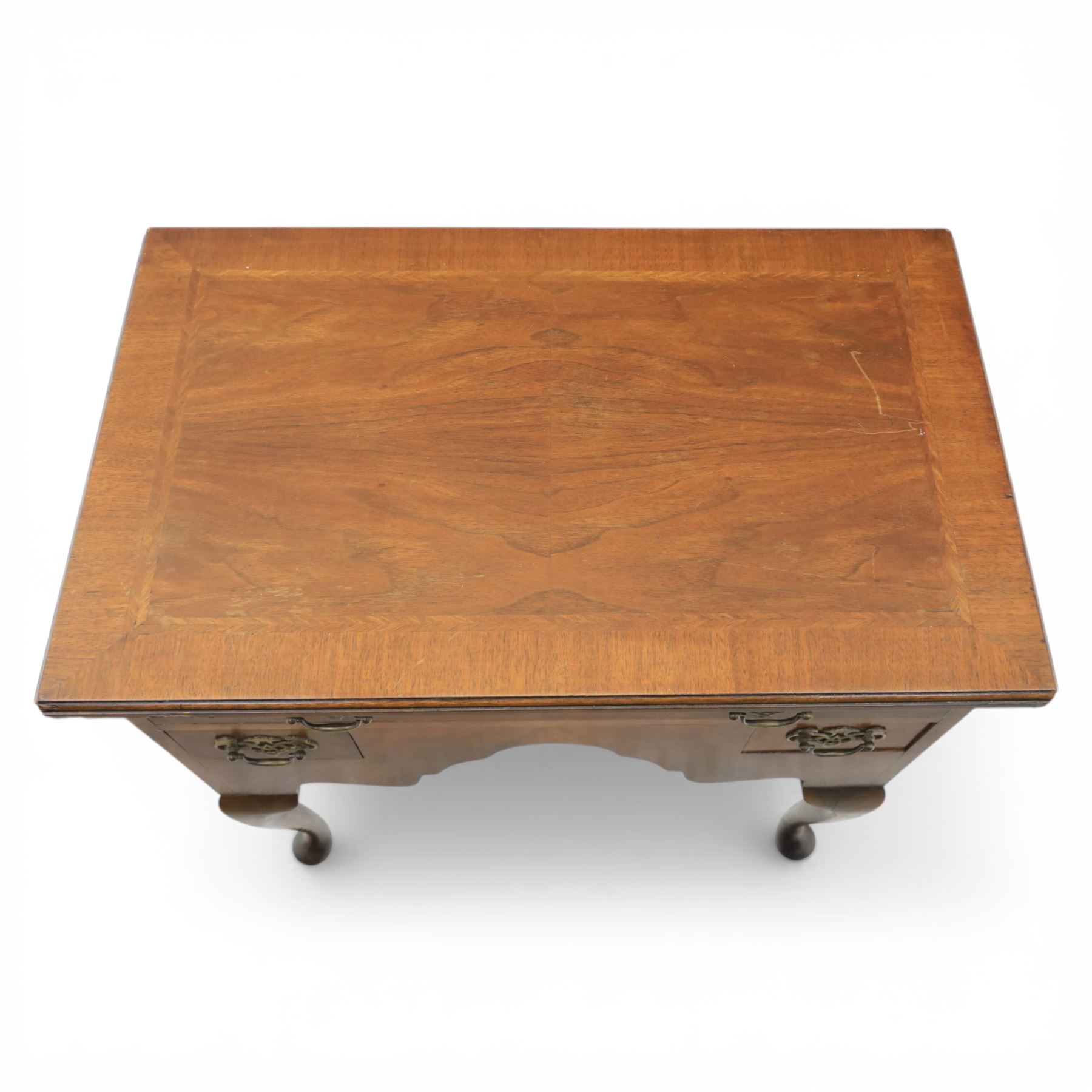 Early 20th century walnut lowboy in Queen Anne style, rectangular crossbanded top over single long drawer and two short drawers with shaped apron, fitted with brass drop handles and backplates, raised on cabriole supports terminating in pad feet