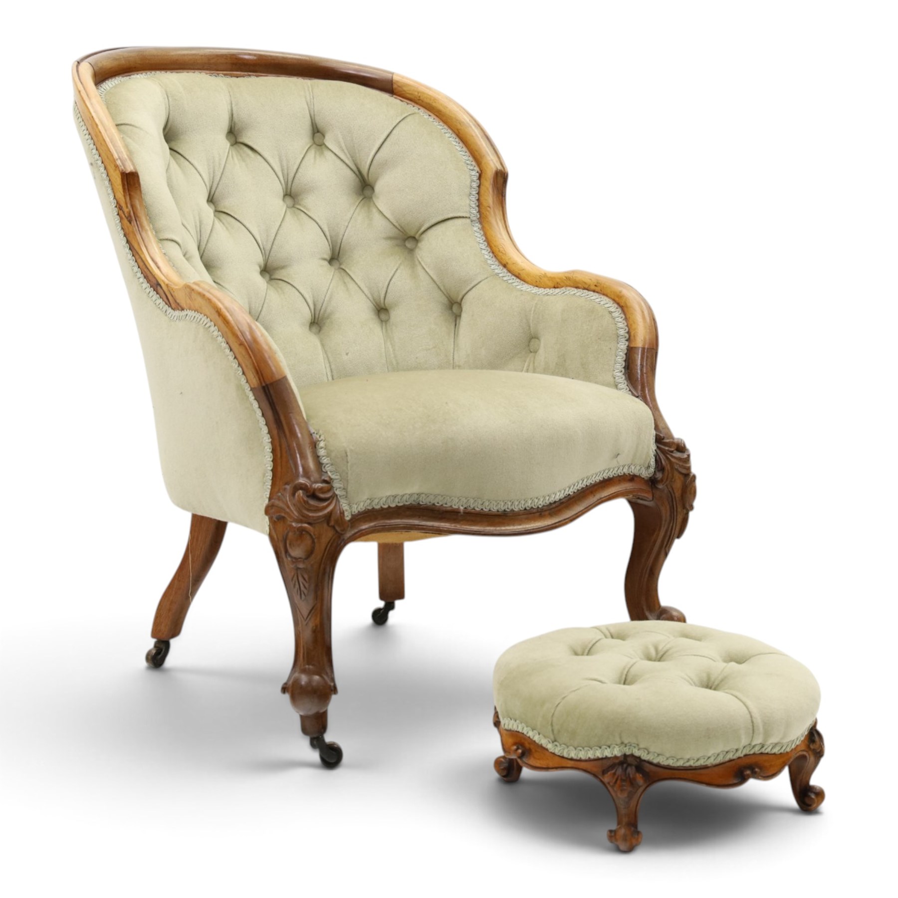 Victorian carved walnut framed armchair with matching stool, the tub-shaped chair with moulded and shaped frame and arm terminals, raised on scrolled cartouche carved supports with scroll feet and castors, buttoned back and sprung seat upholstered in sage green fabric; the small circular footstool with buttoned seat and scroll supports (W36cm H15cm)