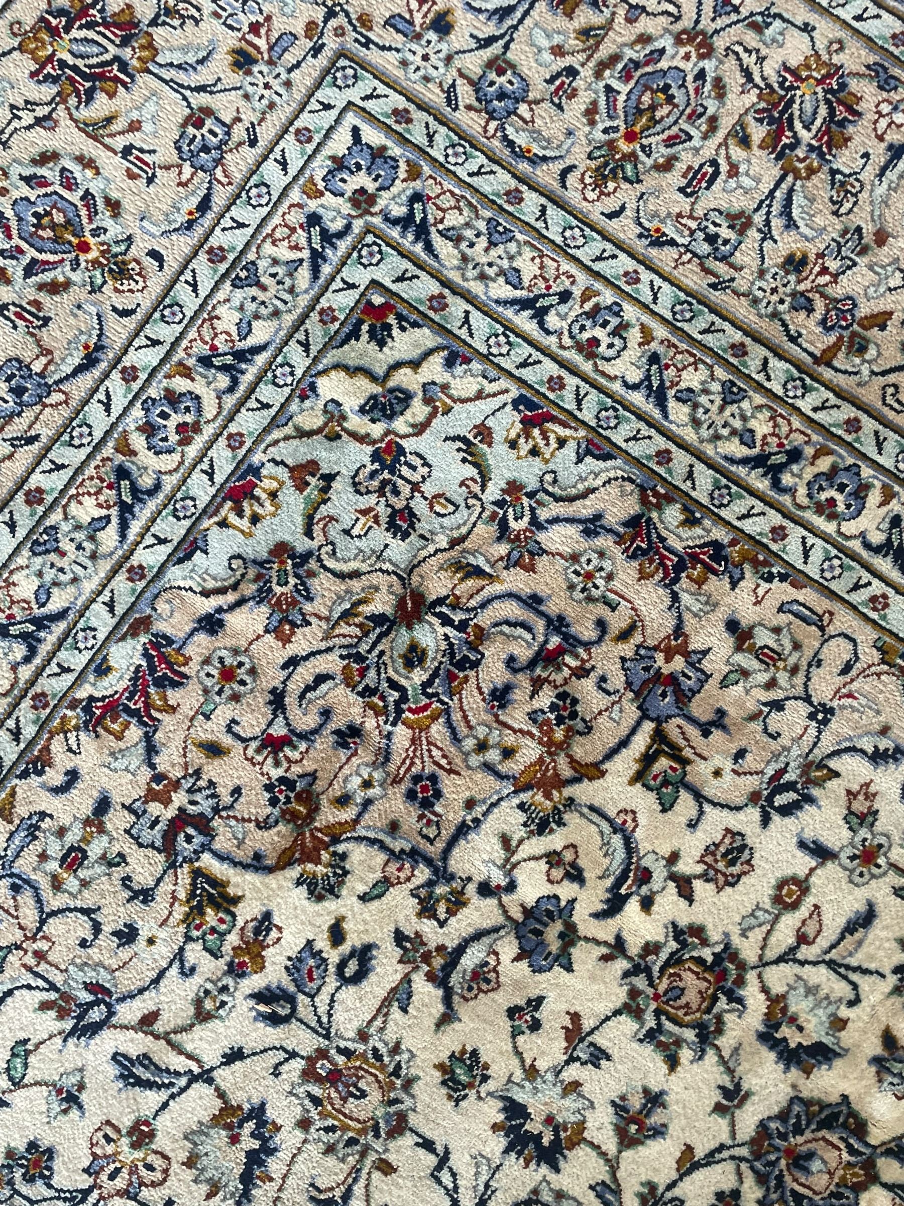 Persian Kashan ivory ground carpet, the field decorated with interlacing foliate branches and stylised plant motifs, scrolling border decorated with repeating palmettes, within floral pattern guard bands