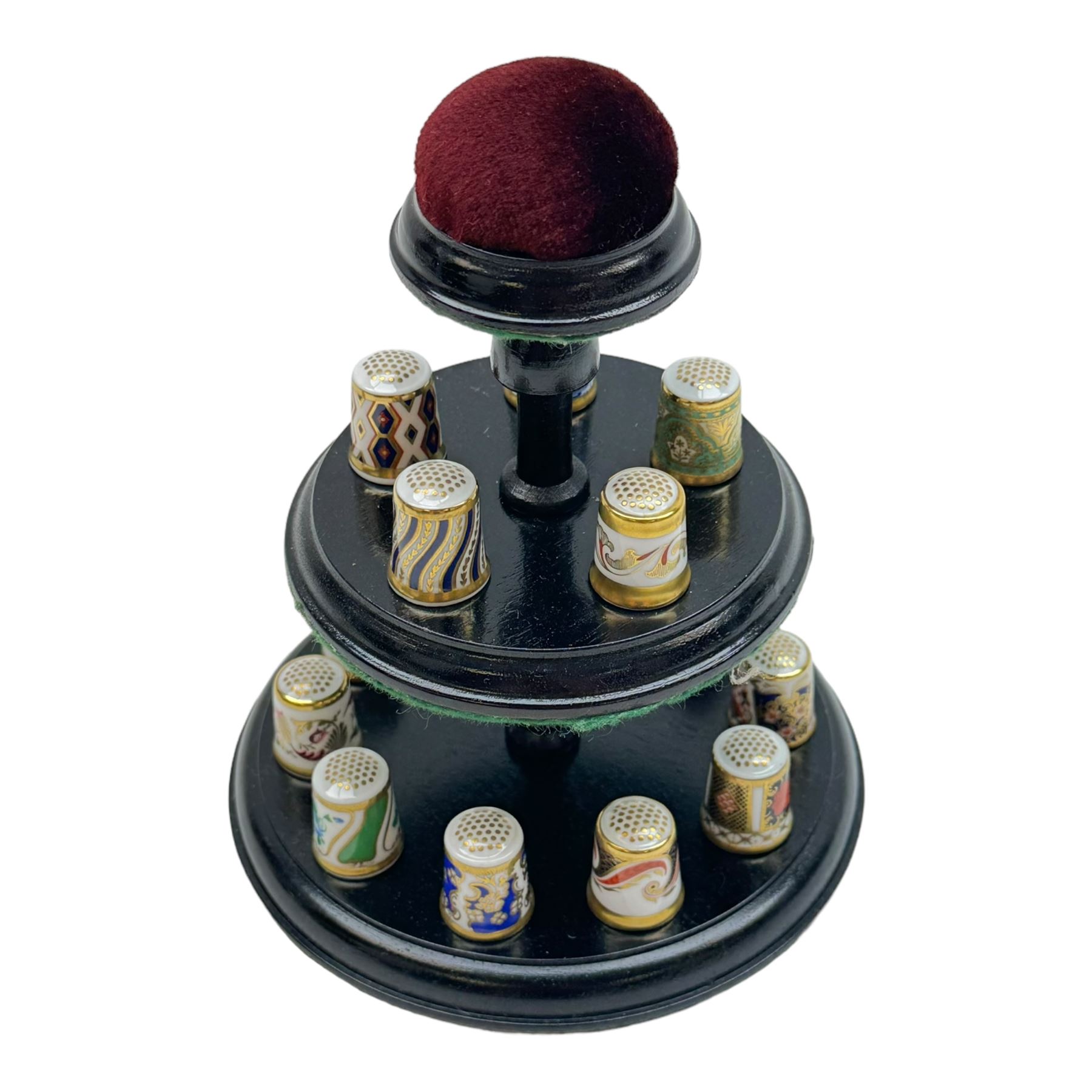 Collection of fifteen Royal Crown Derby thimbles upon an ebonised display stand, together with Royal Crown Derby candle snuffer in Imari pattern 1128