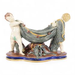 Late 19th century Copeland majolica centrepiece, circa 1874, modelled as two putto standing with fishing net draped between them, their catch spilling onto the quatrelobed base beneath, with impressed mark beneath, H24cm W33cm 
