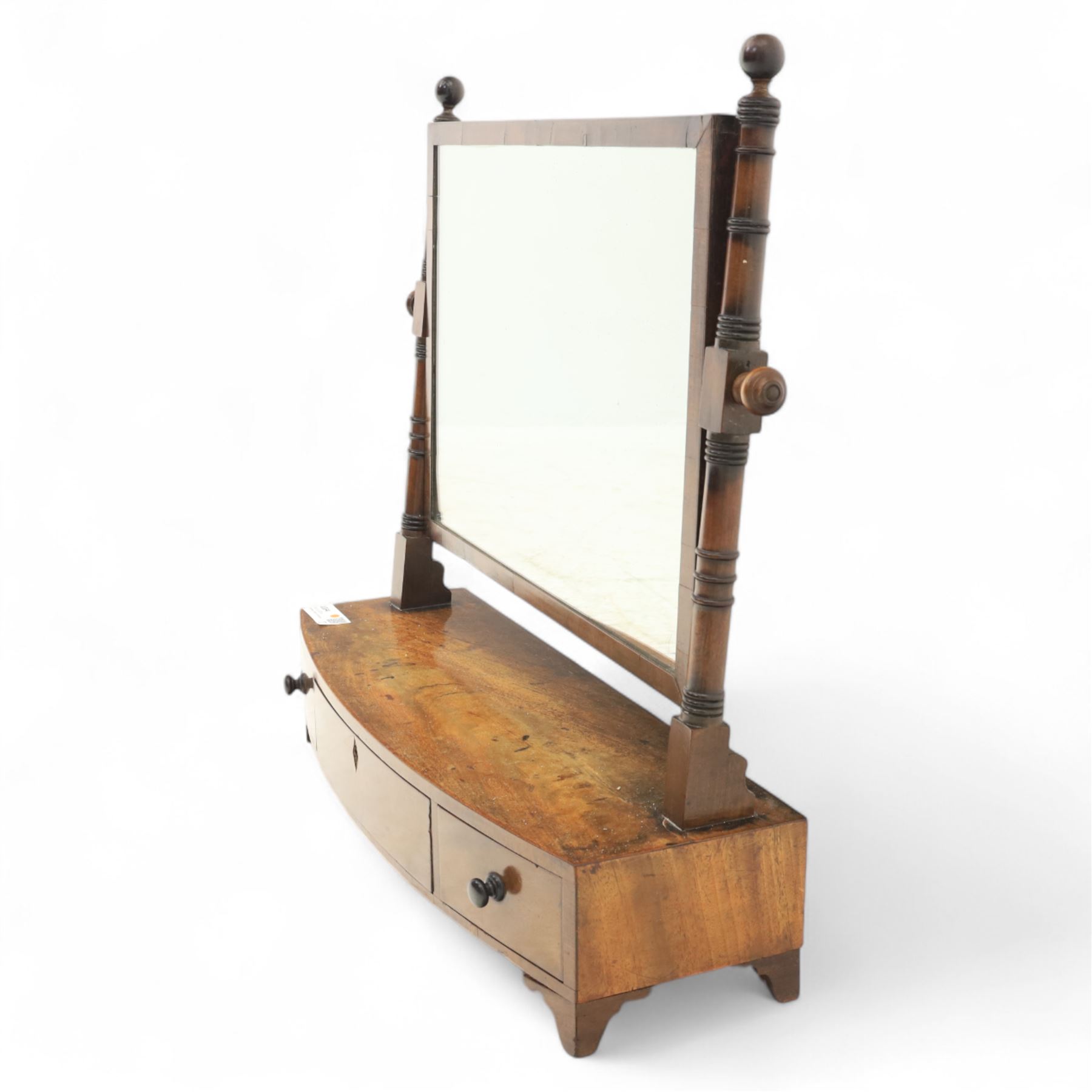 19th century mahogany swing mirror, rectangular frame on turned supports with ball finials, bow front base fitted with three drawers and ebony knob handles, raised on shaped feet