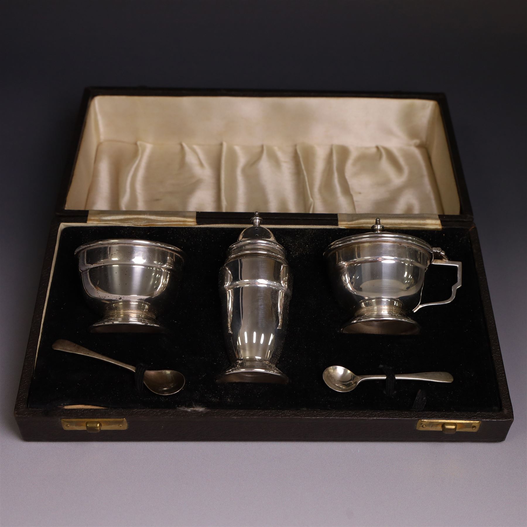 Mid 20th century silver three piece cruet set, comprising mustard pot and cover, pepper pot and open salt, hallmarked Charles S Green & Co Ltd, Birmingham 1947, with blue glass liners and two matched silver condiment spoons, contained within fitted case