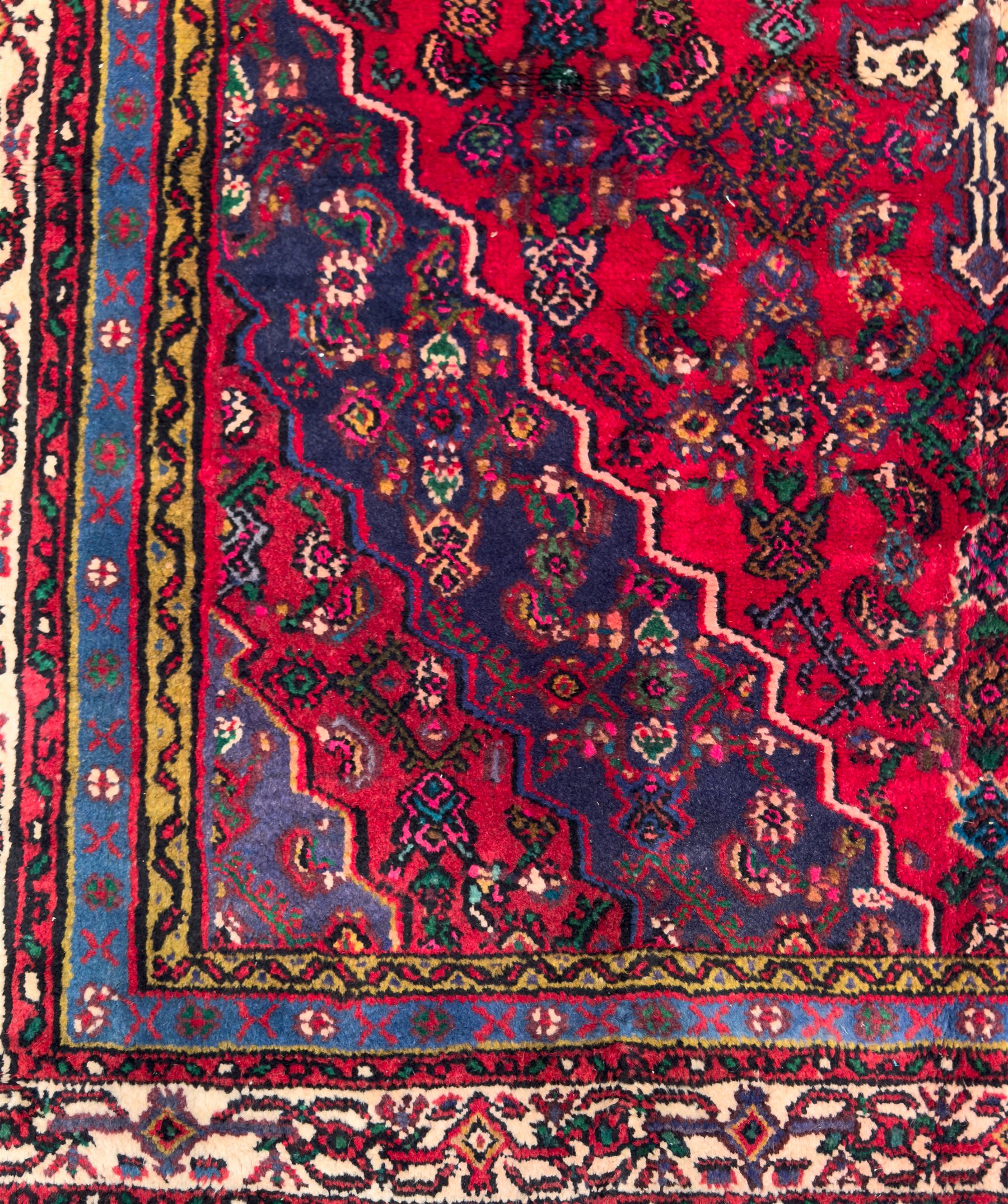 Northwestern Persian Hamadan hand-knotted rug, madder red field with a lozenge medallion enclosing an ivory centrepiece, indigo spandrels within an ivory border of stylized floral motifs between multiple guard borders 