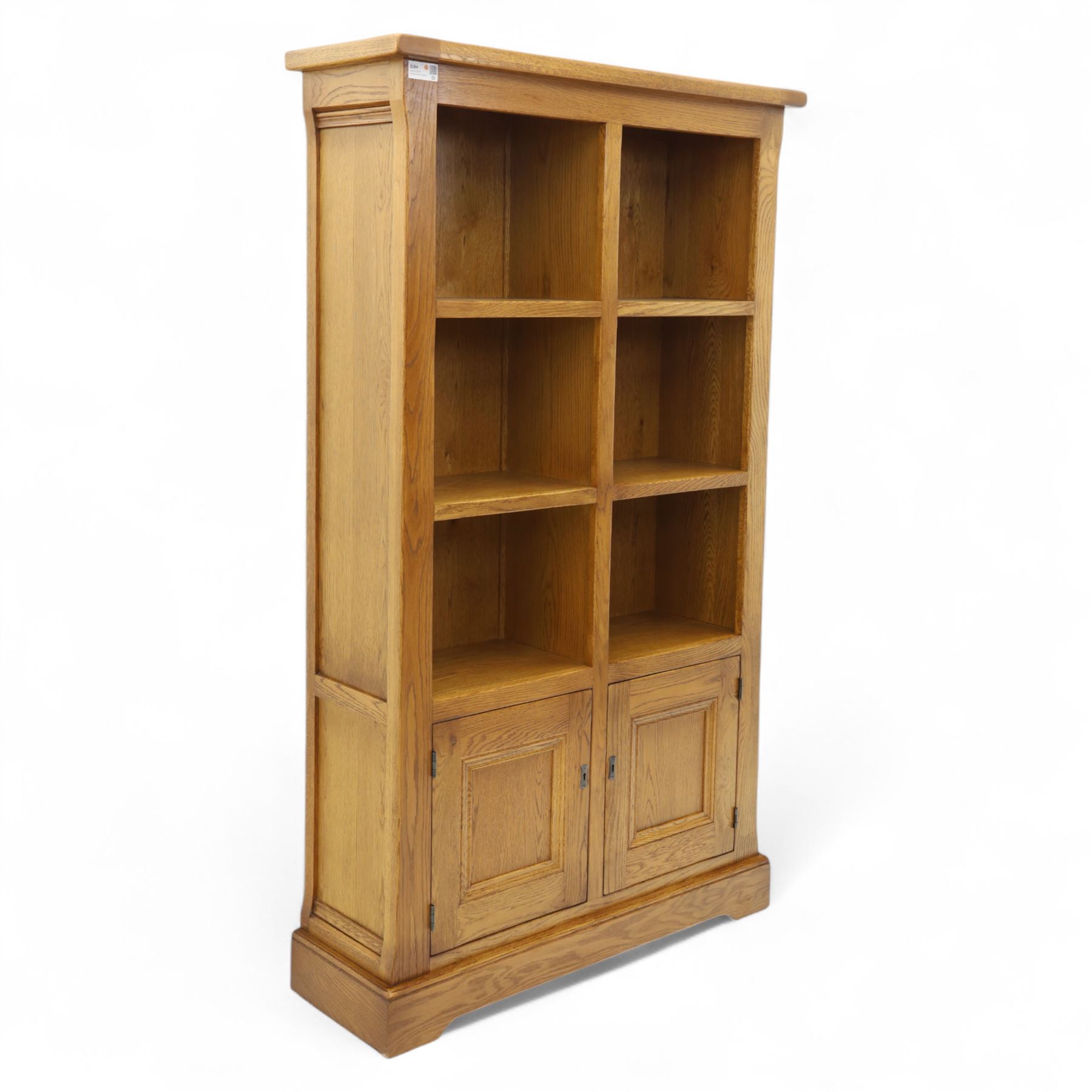 Old Charm - 'Chatsworth' light oak bookcase with two cupboards, featuring two fixed horizontal shelves forming six  rectangular open compartments, over twin panelled cupboard doors, chamfered uprights and plinth base
