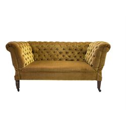 Early 20th century drop-arm chesterfield settee, upholstered in buttoned gold velvet fabric with sprung seat, raised on square tapering supports terminating in ceramic castors