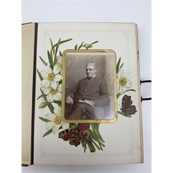  Victorian leather bound photo album, the interior leaves containing apertures of various sizes and shapes of portraits surrounded by printed floral designs, with brass clasp and painted gold decoration to edges, H30cm