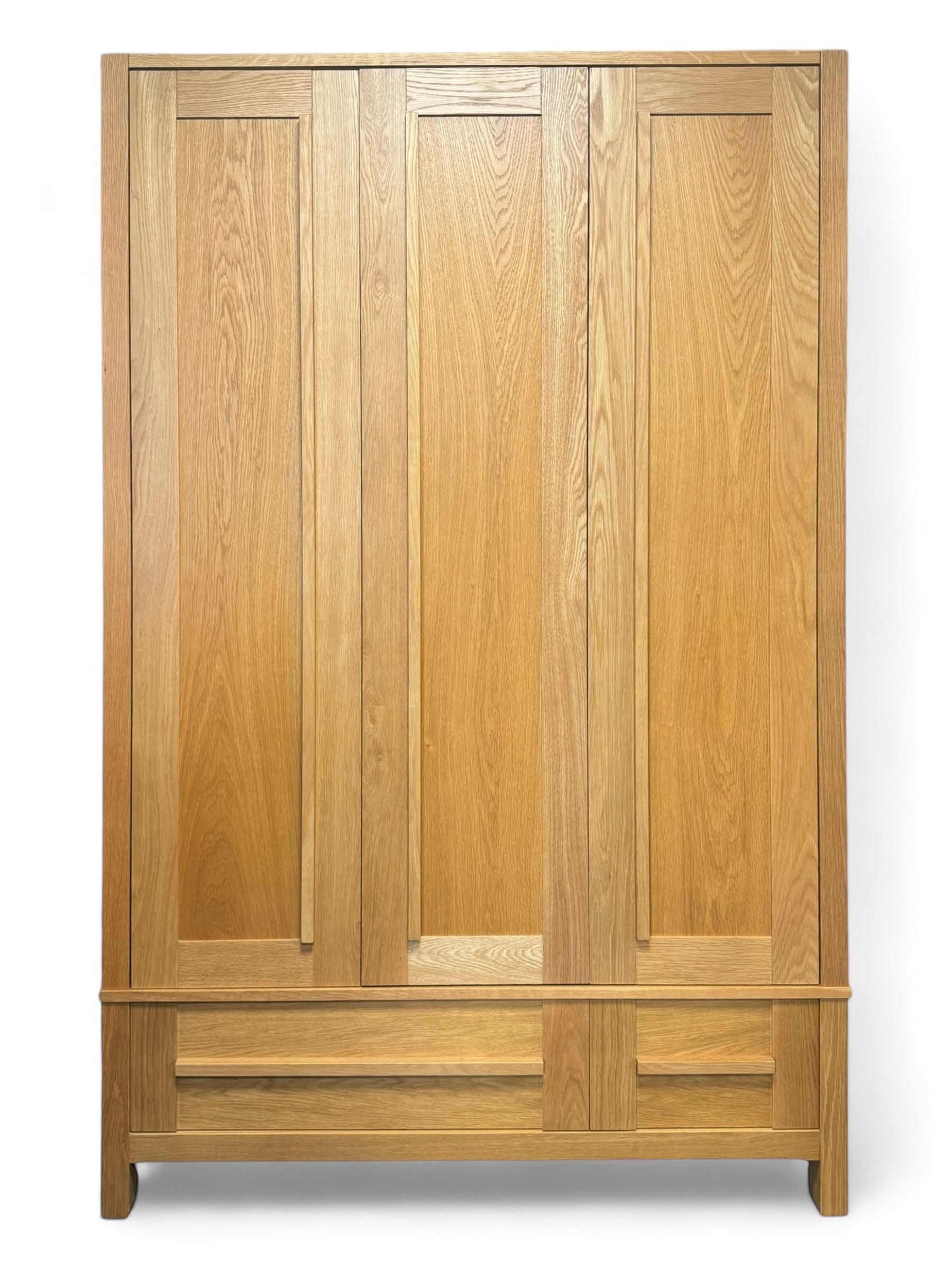 Contemporary light oak triple wardrobe, panelled doors with vertical linear design, left section enclosing hanging rail and single shelf, right section with adjustable shelves, over two drawers, on square stile supports