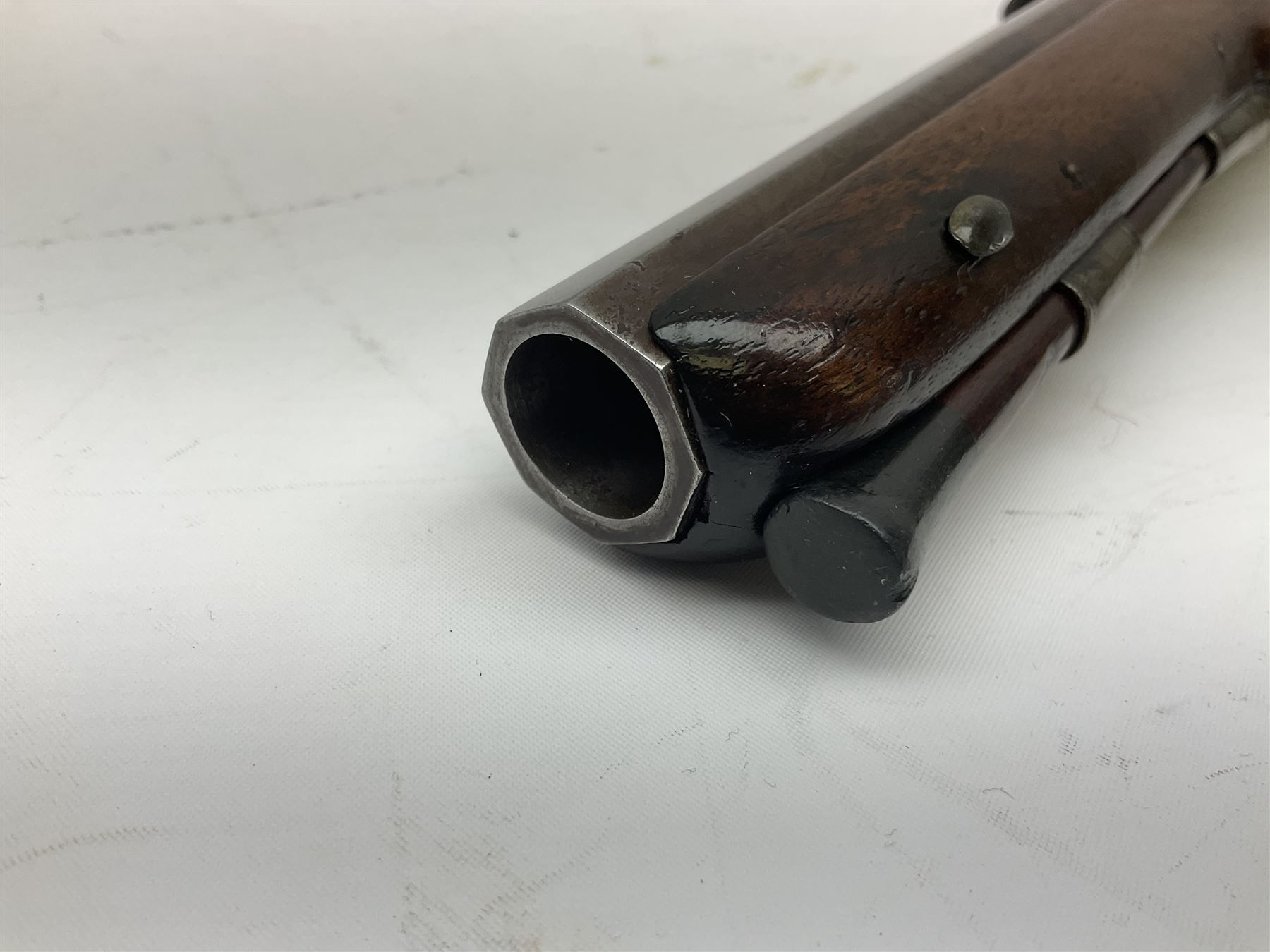 Early 19th century flintlock 16-bore overcoat/duelling pistol by William Bond Lombard Street London, the 23cm octagonal brown stub twist damascus barrel with small foresight, two barrel pins and ram rod under, inscribed Lombard Street London to the top and W. Bond to the action, full walnut stock with lightly engraved steel furniture, pineapple finial and escutcheon, half cock facility L39cm; loose mounted on later mahogany display stand with trade label