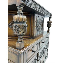 20th century carved oak court cupboard, s-scroll carved frieze over panelled cupboard door carved with arch, lobe and scroll carved cup and cover supports, fitted with three drawers and three cupboards below
