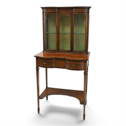Edwardian inlaid mahogany serpentine-front side cabinet, raised back with central glazed door flanked by bow-front glass panels, the base fitted with banded and shaped frieze drawer, on square tapering supports united by concave under-tier